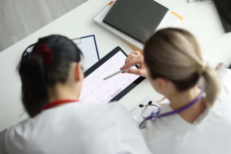 Two doctors reviewing medical data on a tablet device.