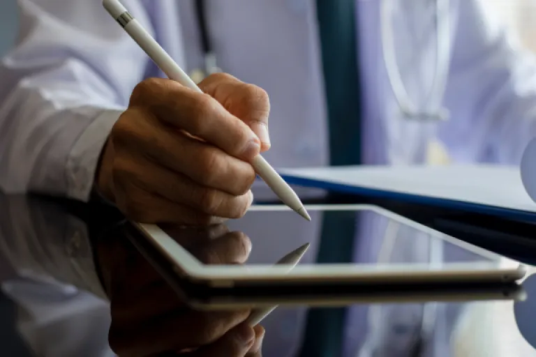 Doctor writing something down on a tablet.