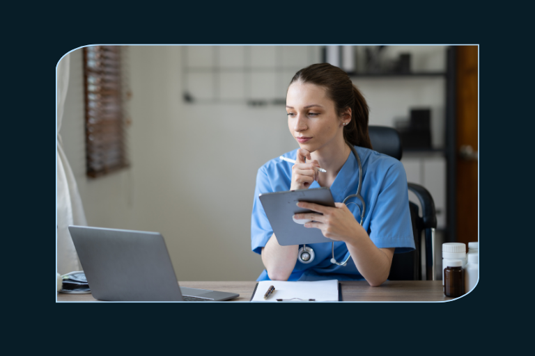 Female medical professional viewing a laptop and a tablet.